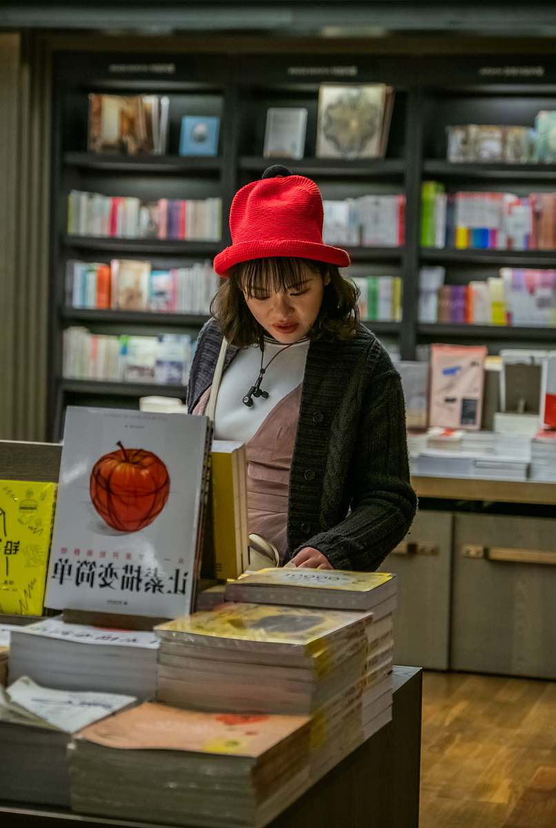indoors woman with red hat checking books on display clothing