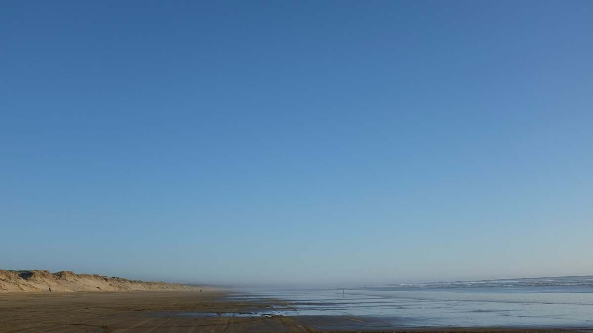 ocean body of water and gray seashore under blue sky blue