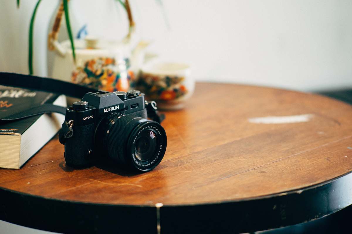 tabletop black DSLR camera on top of brown wooden table fujifilm camera