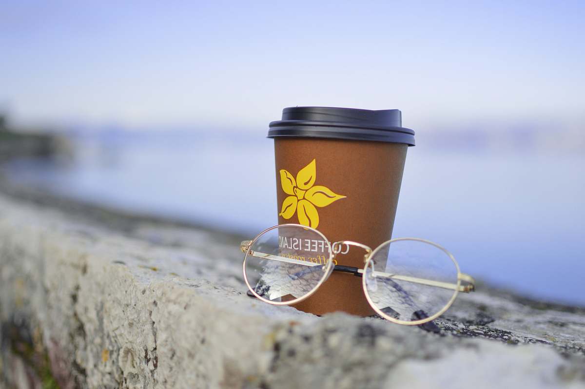 corfu gold-colored framed eyeglasses beside plastic disposable cup greece