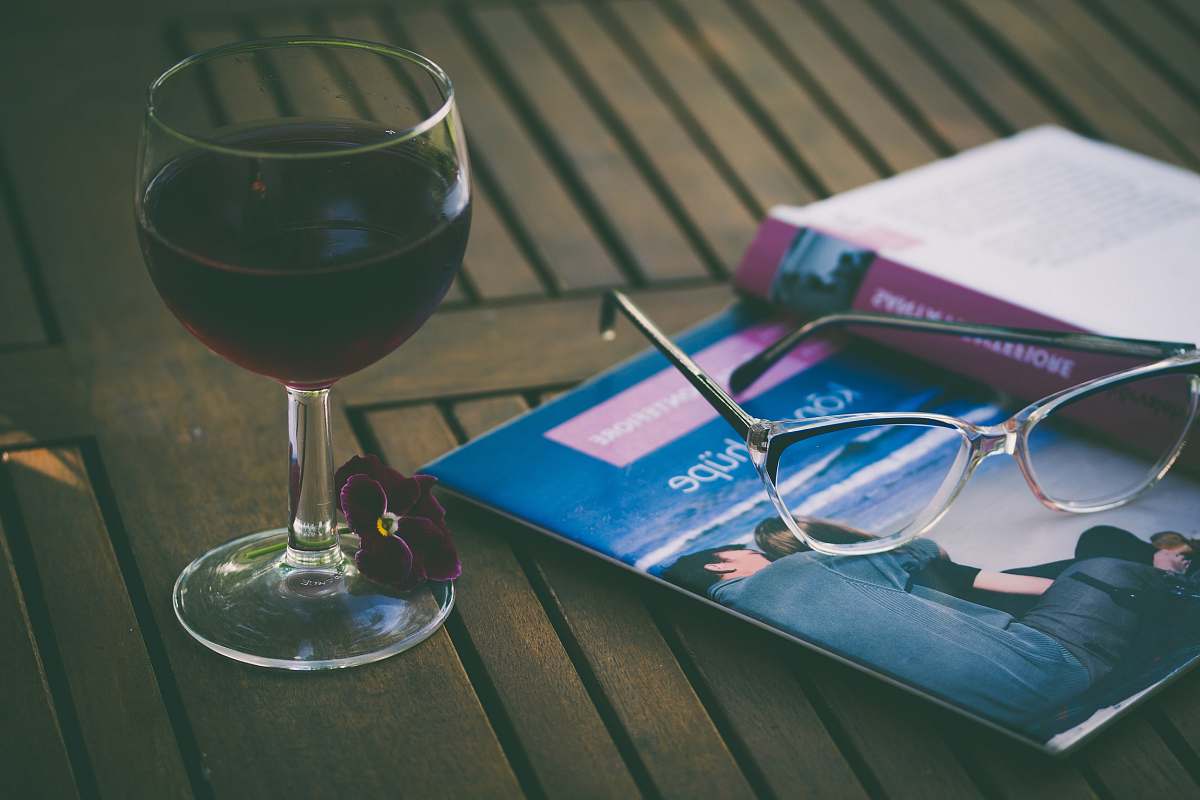 wine silver framed Wayfarer-style eyeglass on blue book wineglass