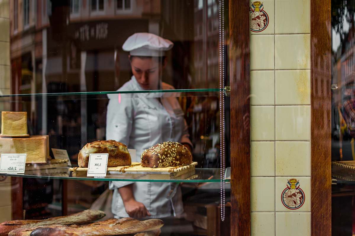person baker inside glass covered store bakery