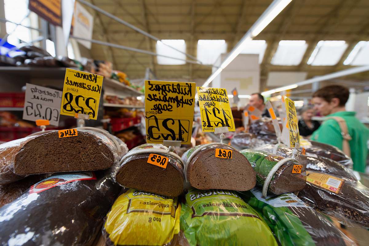 Discover a lively market scene showcasing an array of apparel packs with clear pricing, alongside a mouthwatering display of fresh bread and pastries. This captivating image is perfect for illustrating themes of shopping, local markets, and the delightful intersection of fashion and food. Ideal for advertisements, blog posts, or articles related to retail, culinary experiences, and community markets.