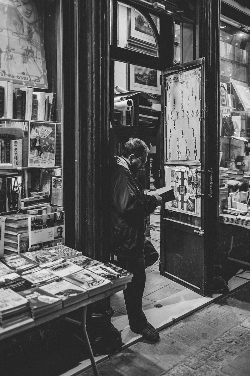 person man leaning on open door frame black-and-white