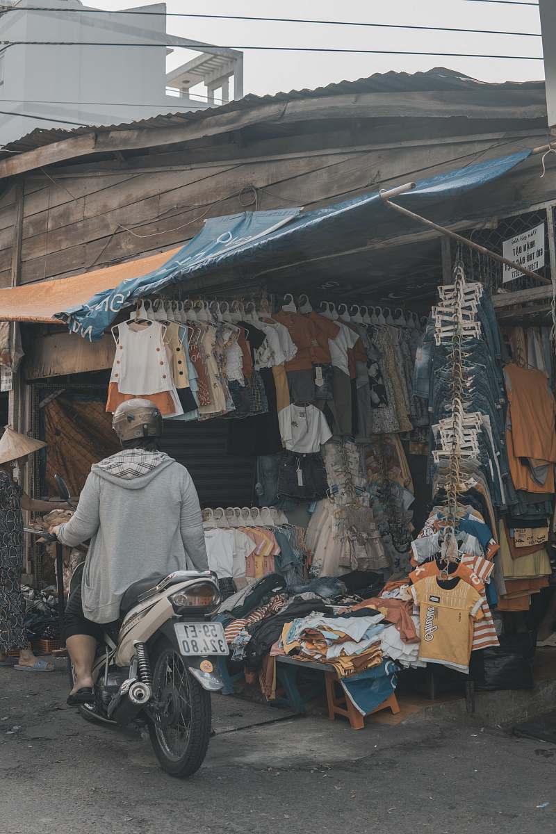 person person riding on motorcycle beside clothes display market