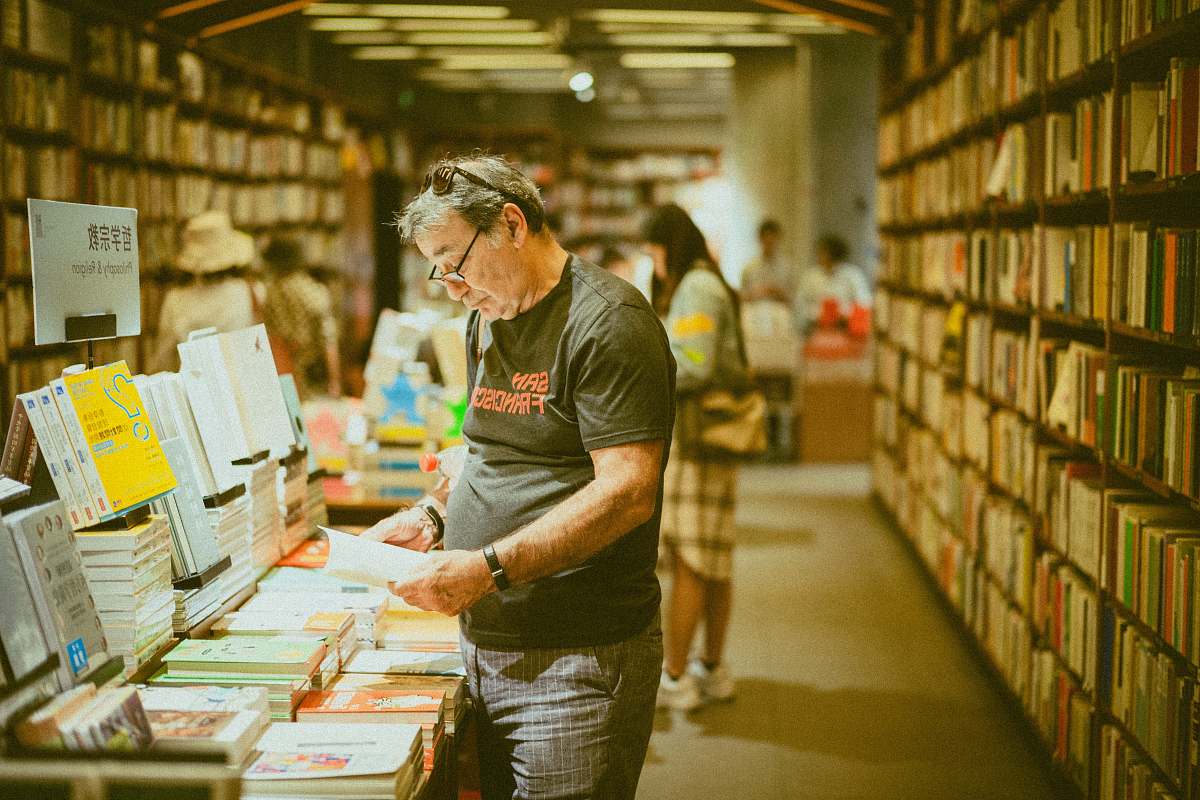 person selective focus photography of standing person holding book indoors