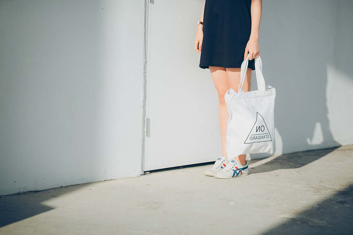 person woman holding bag while standing near wall bag