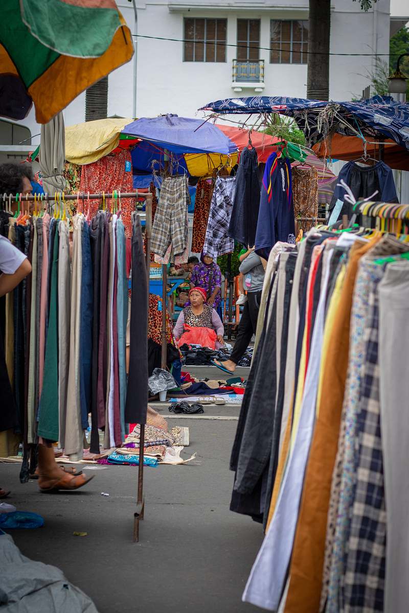 apparel woman sitting while surrounded by clothes clothing