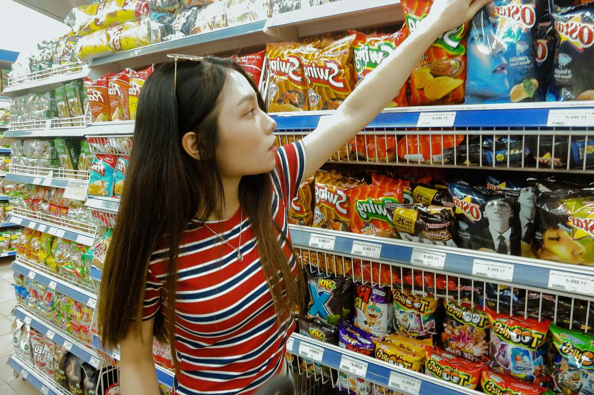 person woman standing while grabbing plastic pack grocery store