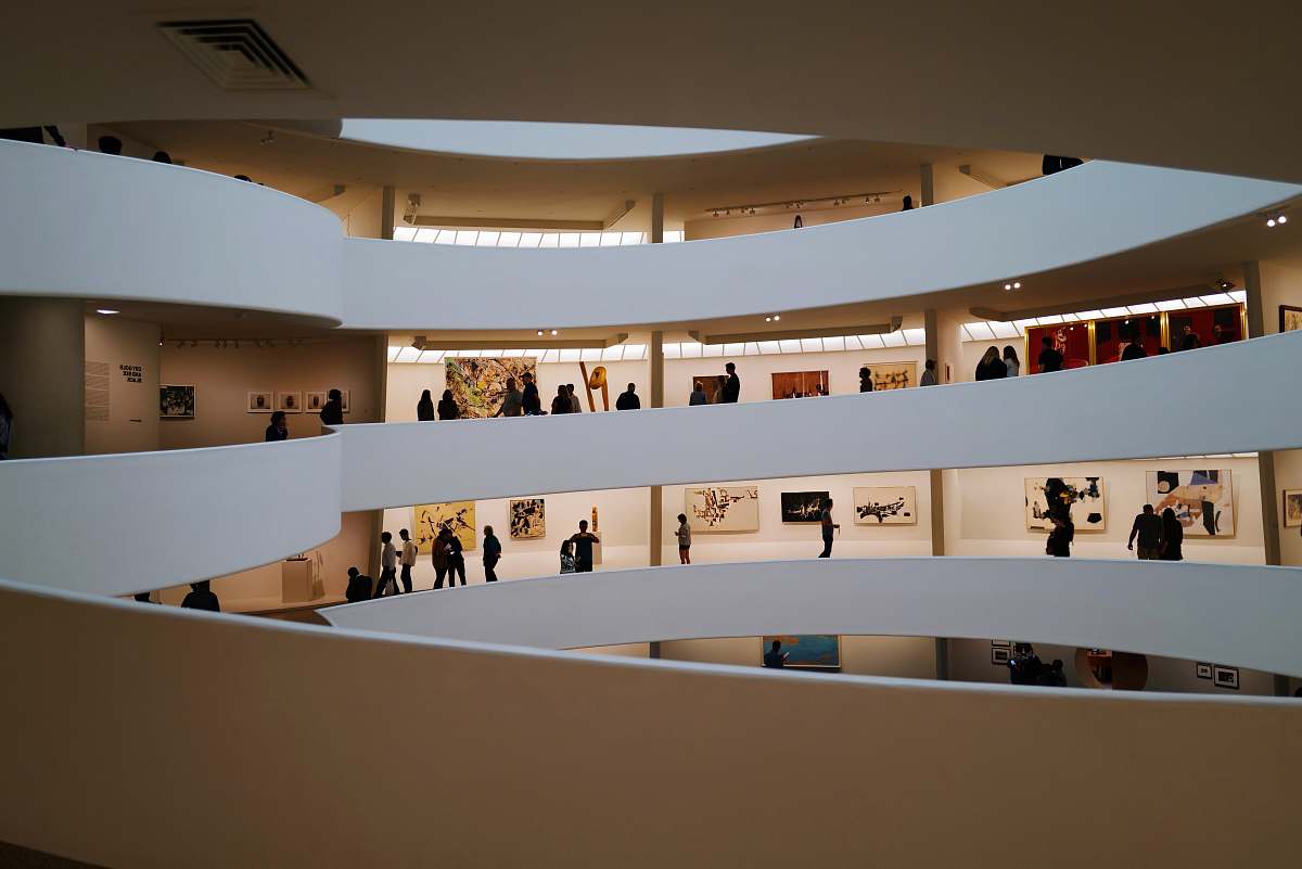 banister people walking inside building with paintings handrail