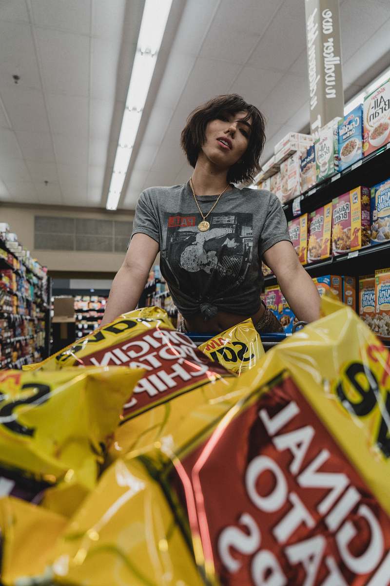 human woman standing in front of chip bags inside store grocery store