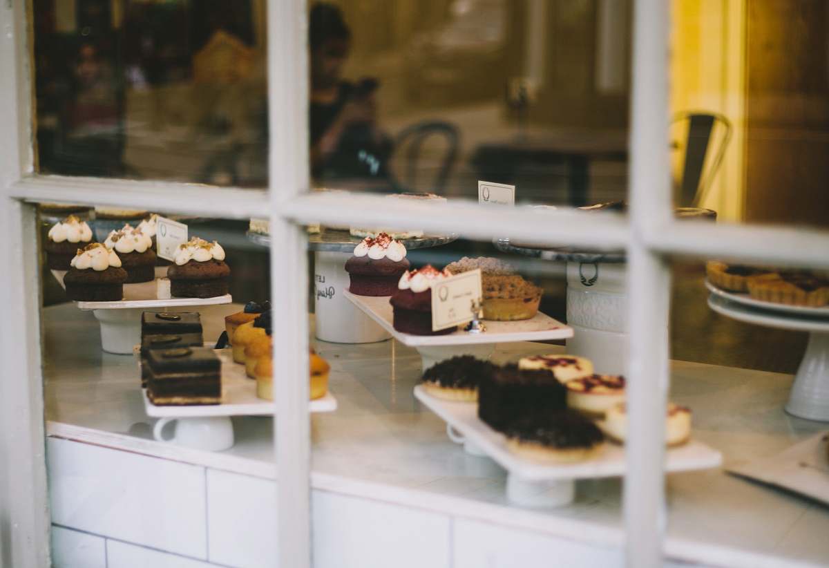 human assorted cakes near window bakery