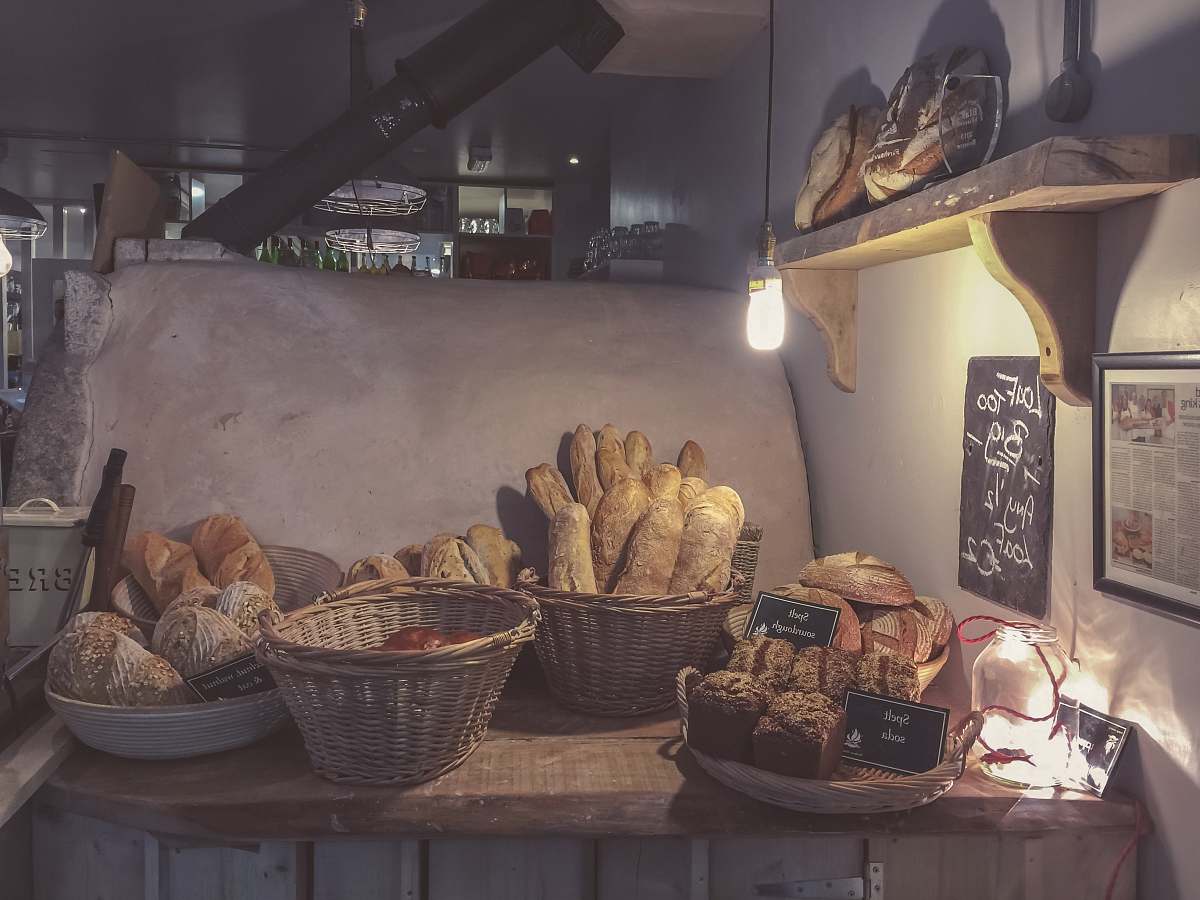 bakery breads in brown wicker basket on top of brown wooden table bread