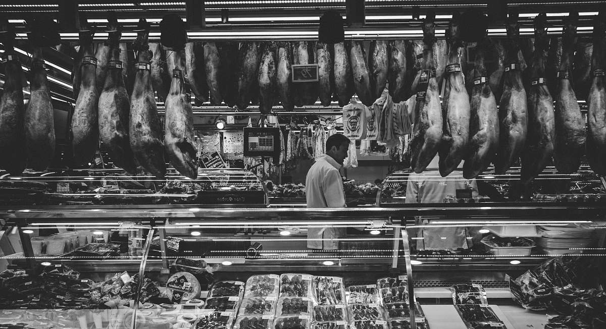 black-and-white grayscale photography of man standing in store butcher shop