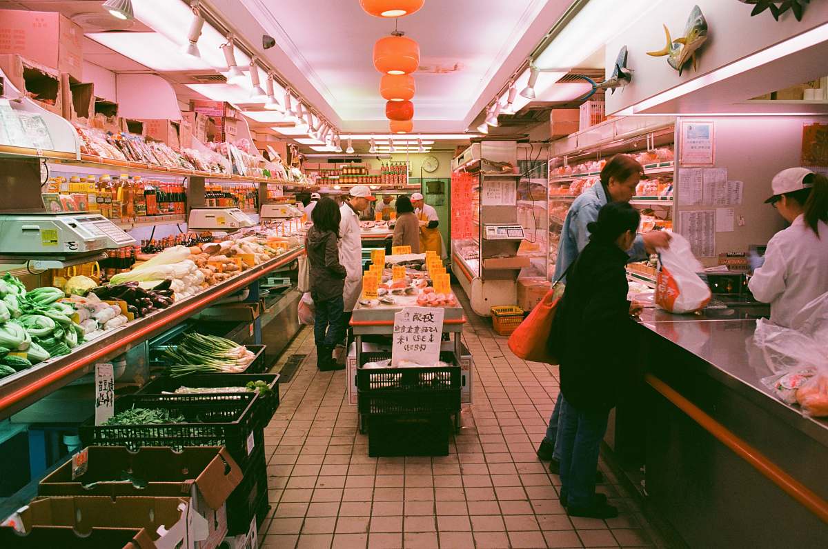 person man stands beside man in front of cashier in store grocery store