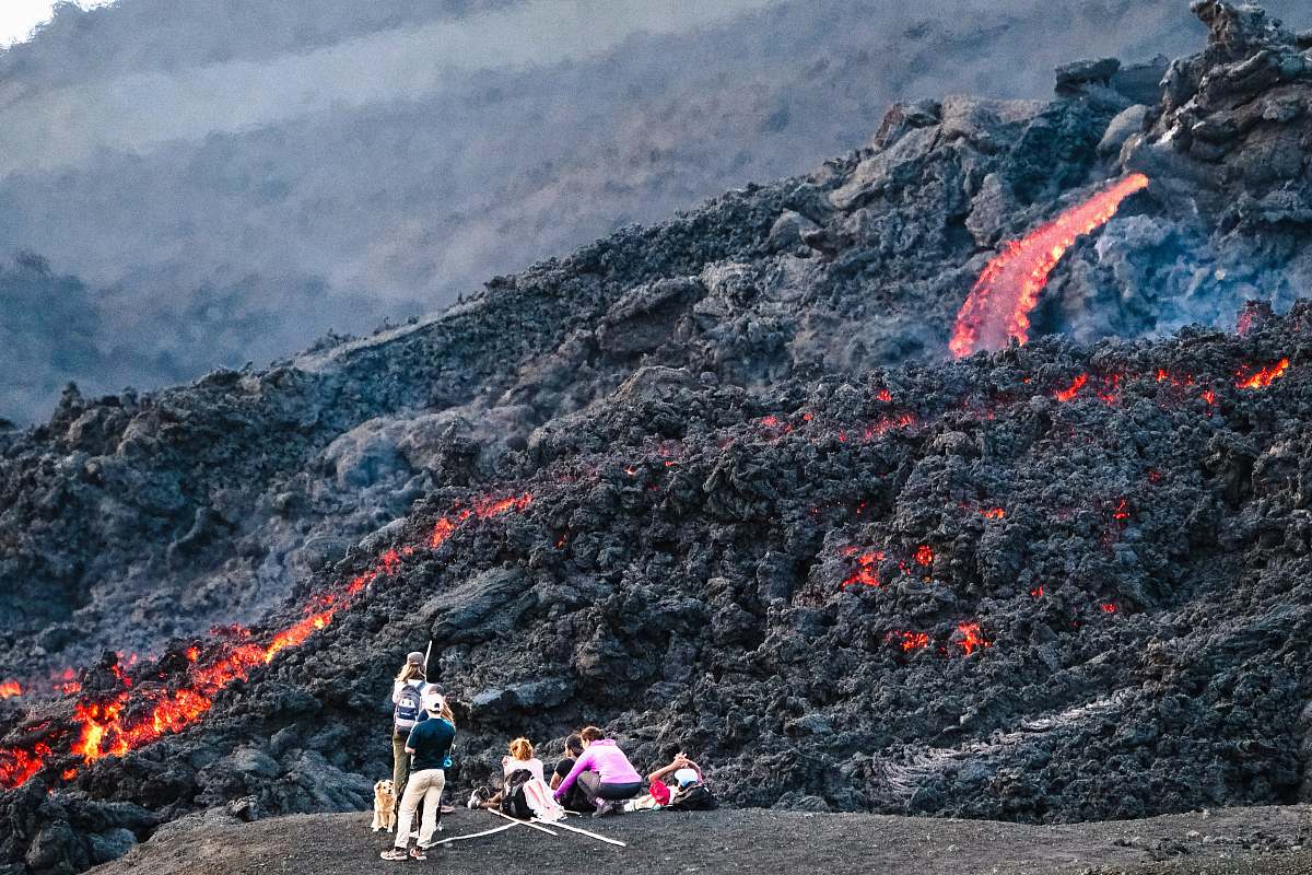 mountain photography of people standing beside lava during daytime outdoors