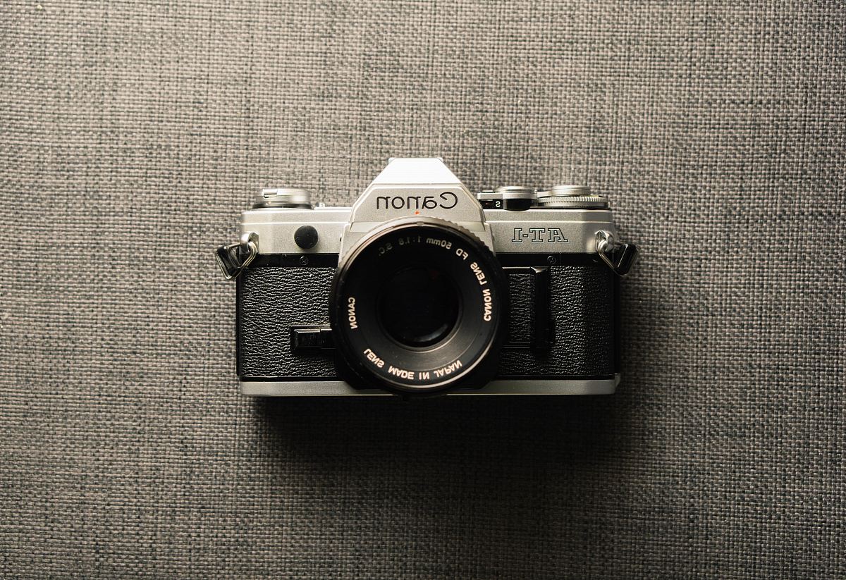 black and gray Canon camera on gray textile