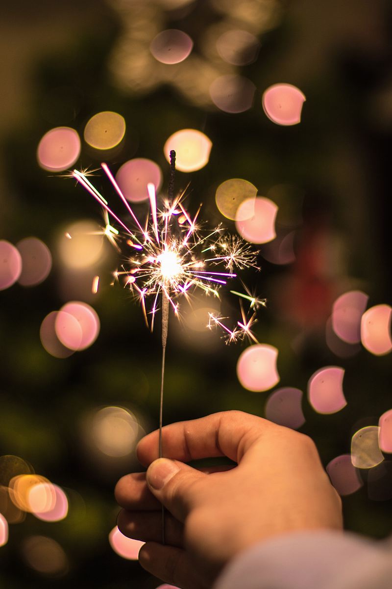 bokeh photography of person holding fireworks