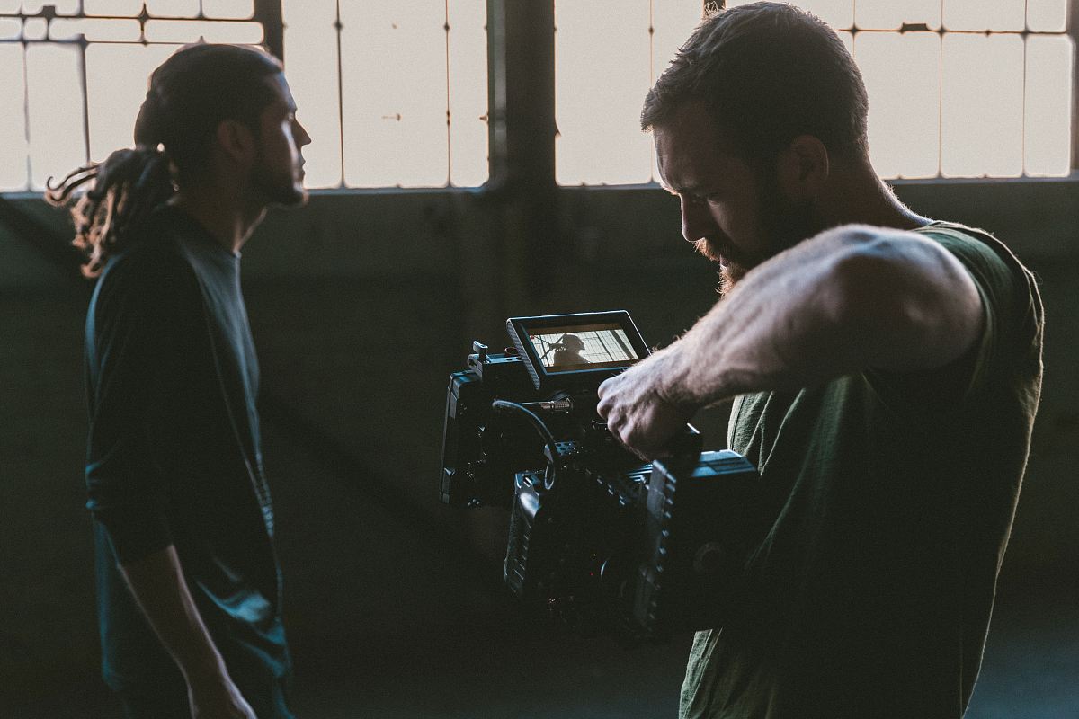 man holding camcorder with man near wall