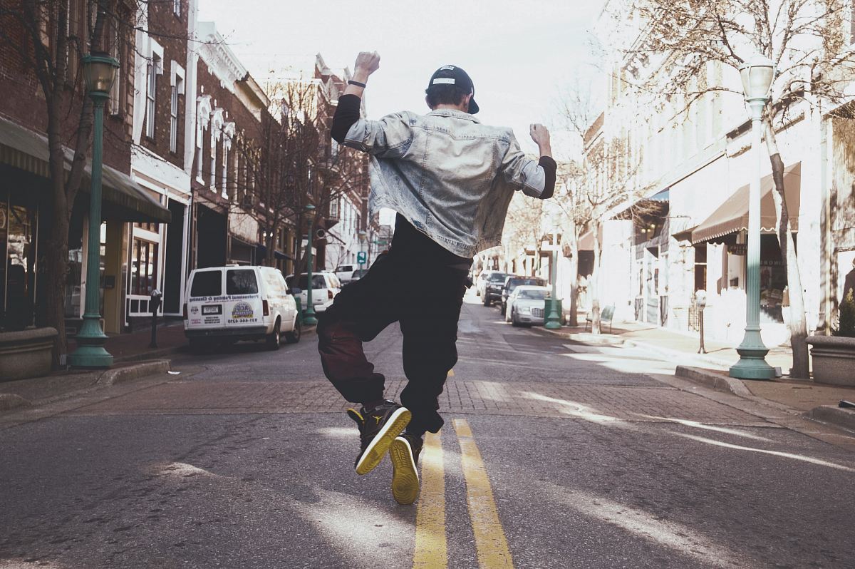 man jumping on the middle of the street during daytime