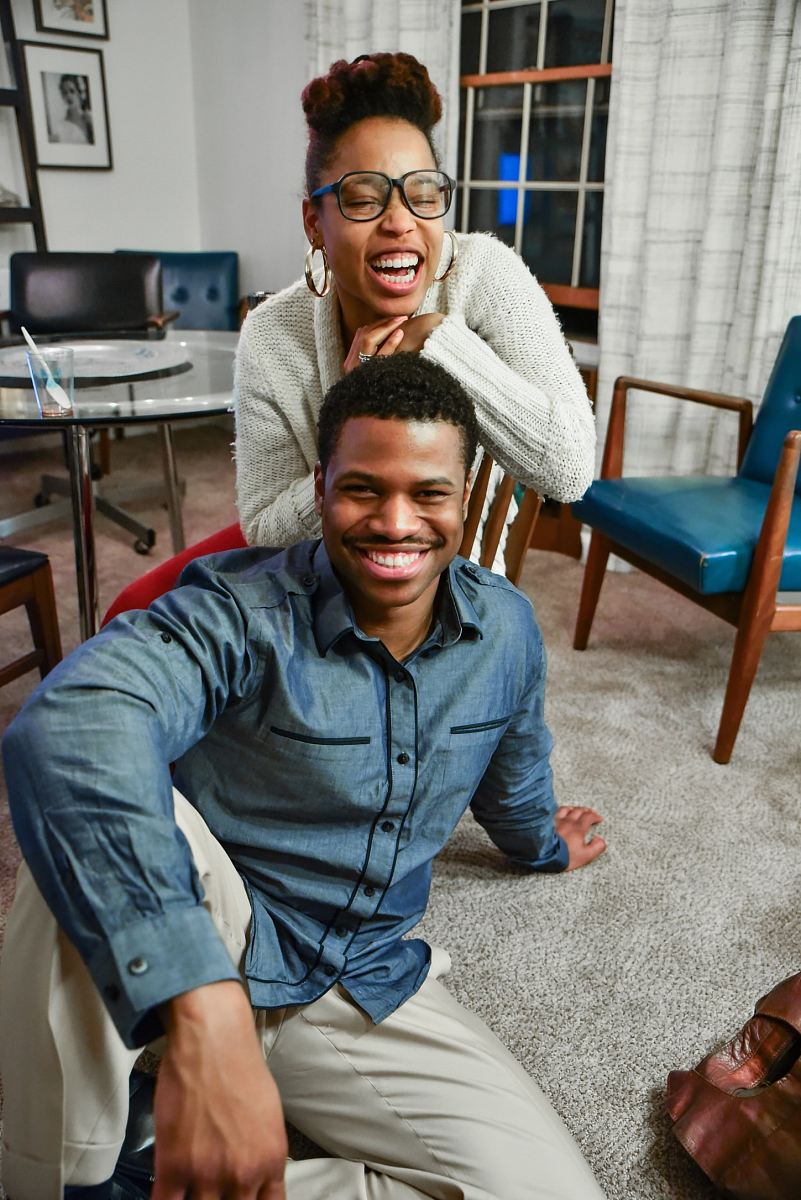 man sitting on floor beside woman smiling inside white painted room