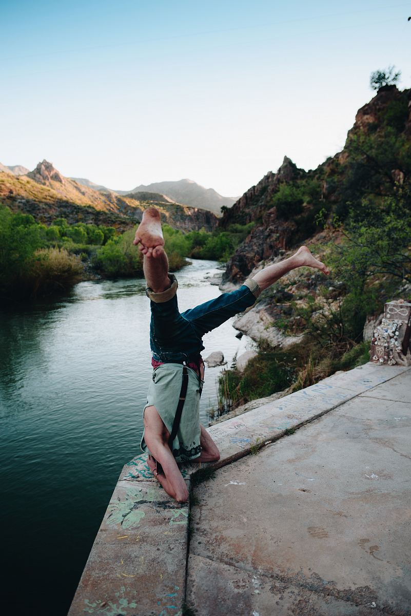 person in gray top doing headstand in front of body of water