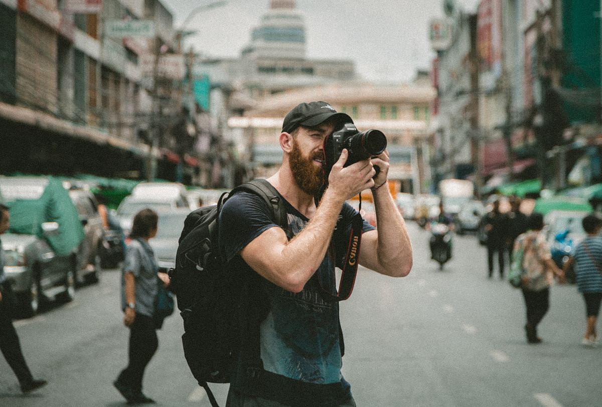 shallow focus photography of man using a DSLR camera