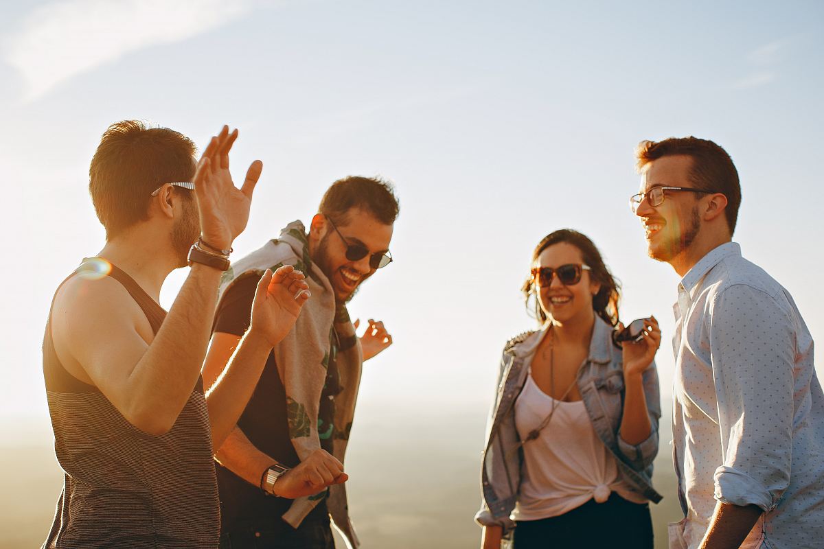 three men and one woman laughing during daytime