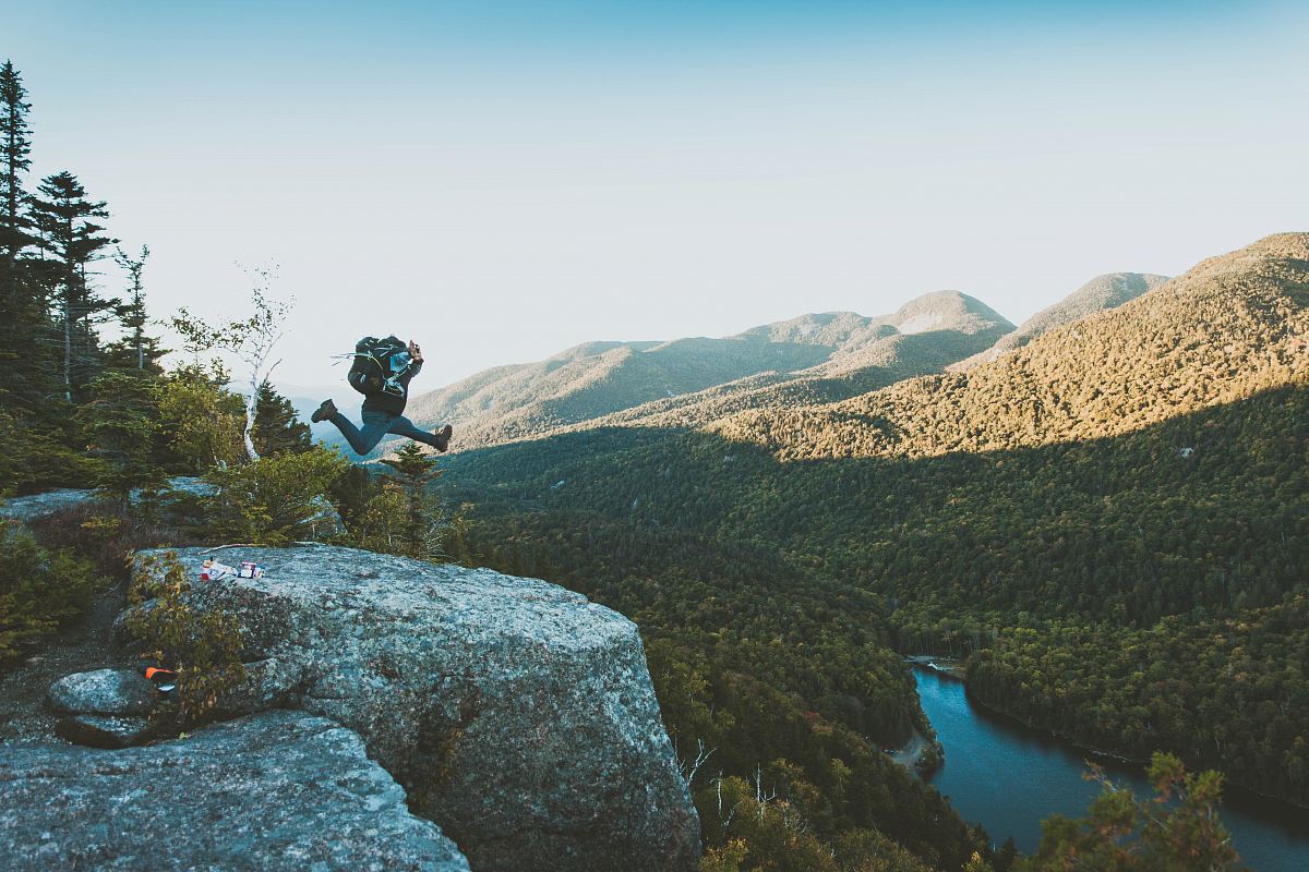 time lapse photo of person jumping from cliff within mountain range