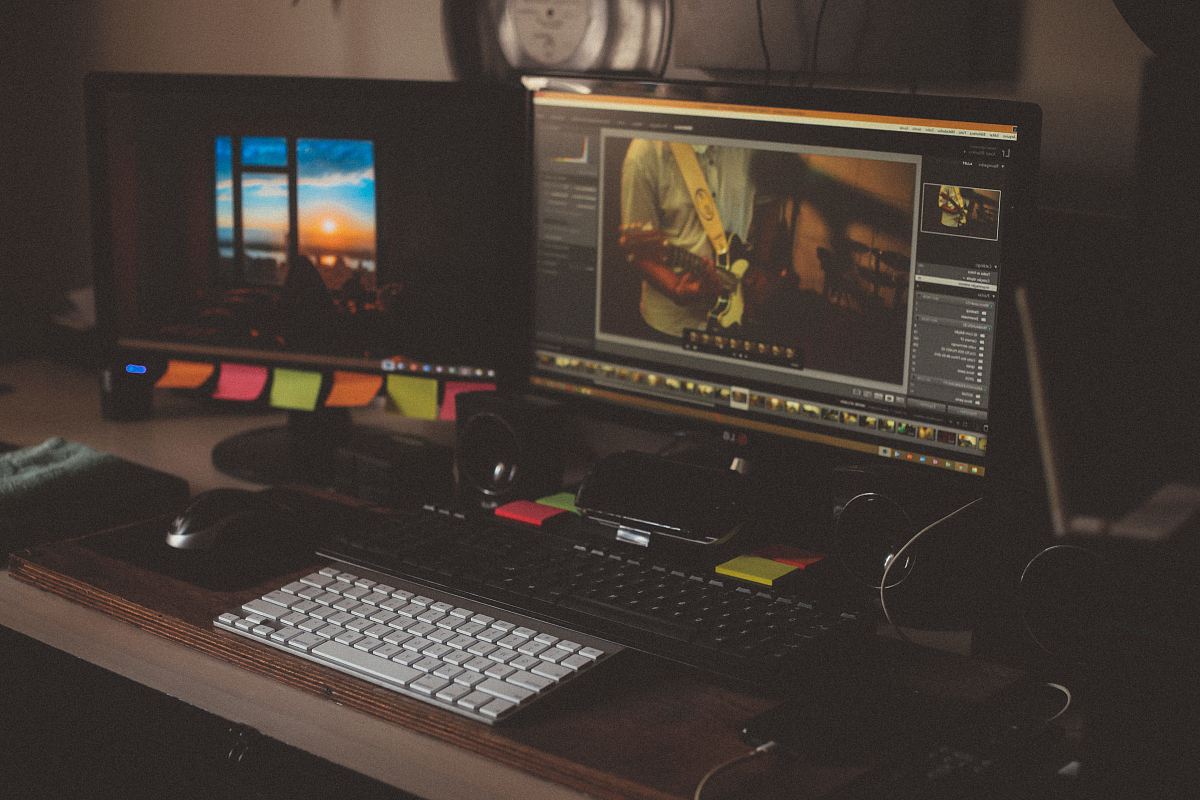 turned on two computer monitors beside two black and white keyboards on desk