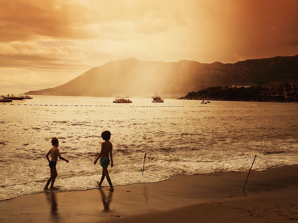 two children walking on beach during sunset