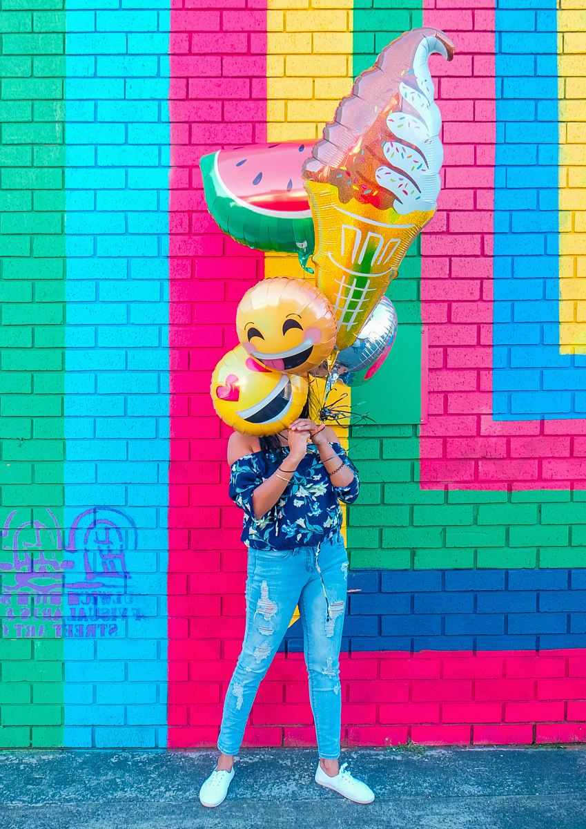 woman covering face with assorted ballons