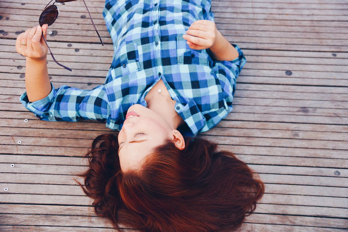woman in blue flannel shirt laying on floor