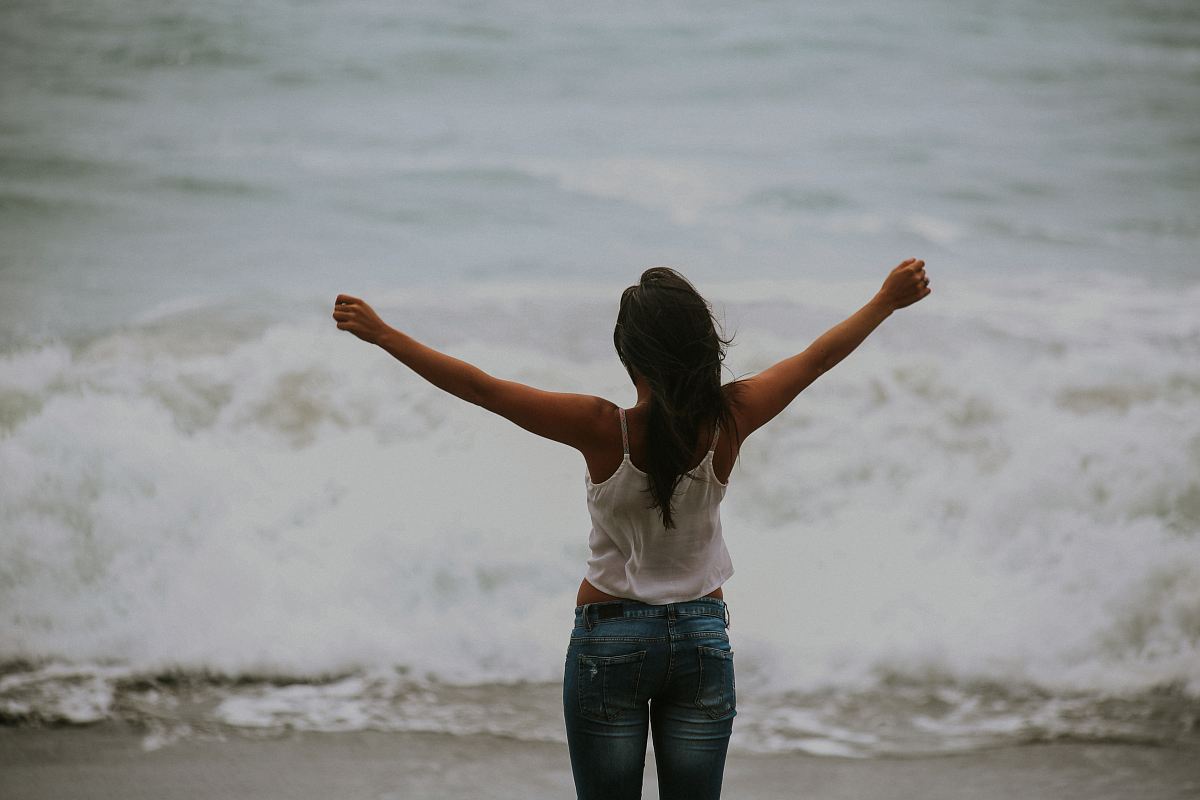 woman in white spaghetti strap top standing on the seashore