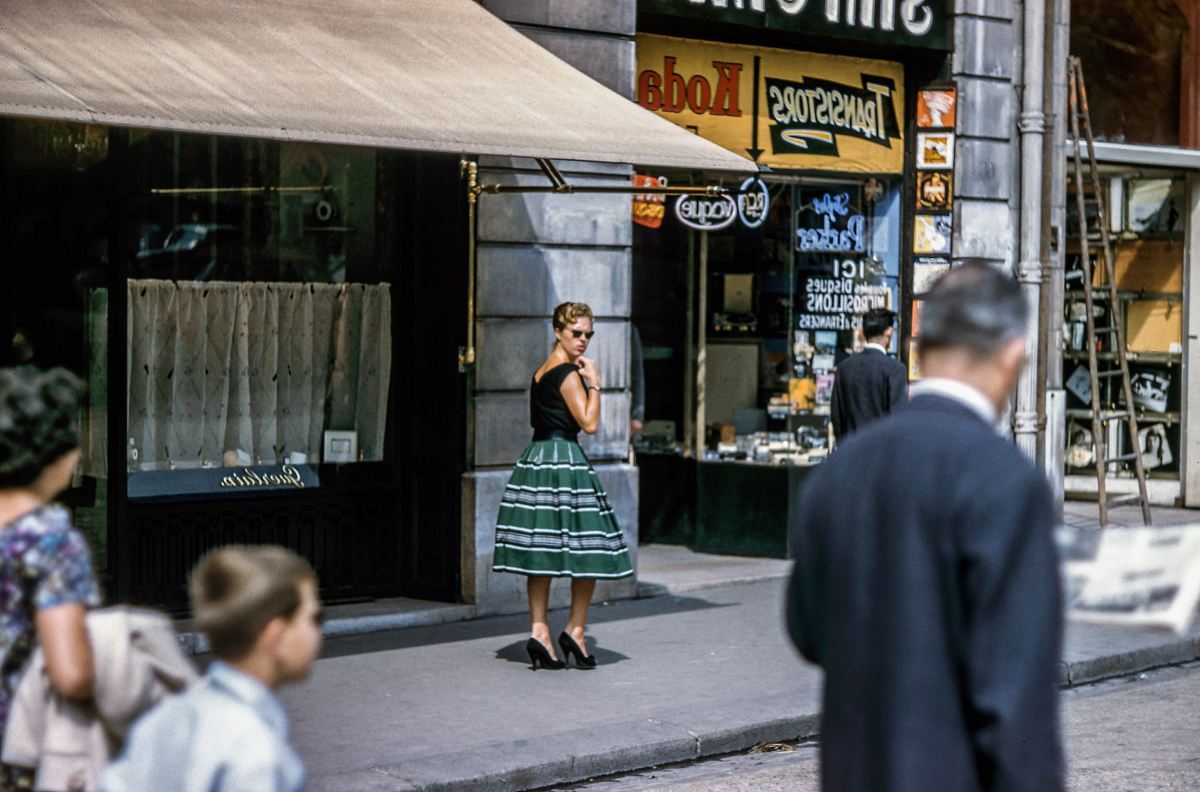 woman looking left while standing beside store along the road