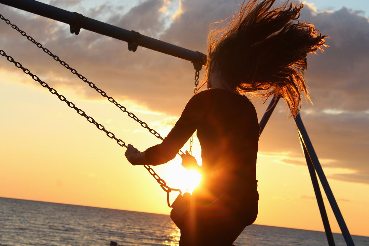 woman riding on swing during sunset