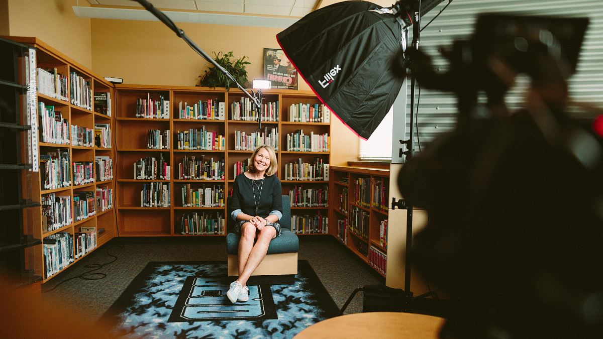 woman sitting on armless chair with light between bookcases in room