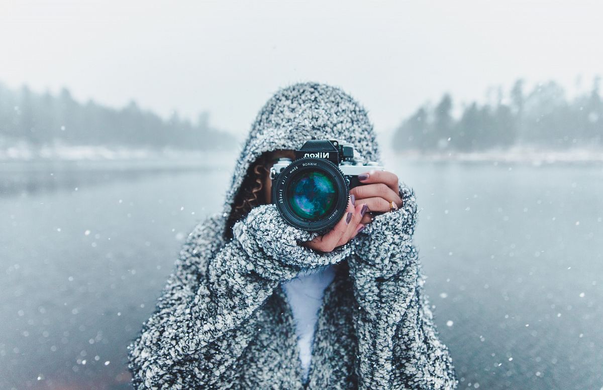 Discover the serene beauty of winter as a woman skillfully uses her Nikon DSLR camera to capture the enchanting scene of a snowy lake. This striking image not only reflects the tranquility of nature but also serves as an inspiration for photography enthusiasts and nature lovers alike, perfect for promotional materials, blogs, or art prints.