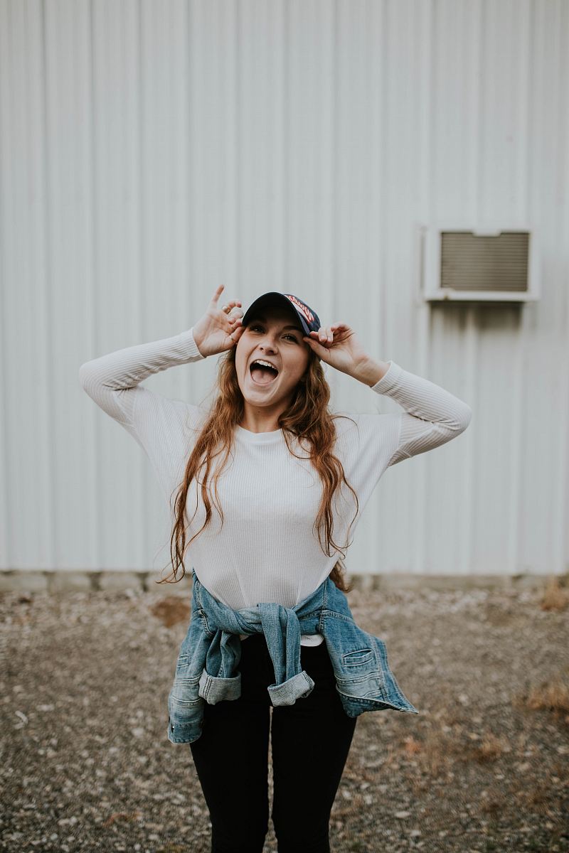 woman wearing black cap standing outside the house while laughing