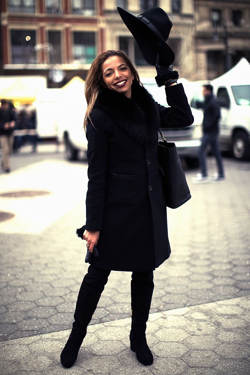 woman wearing black coat standing on gray concrete pavement