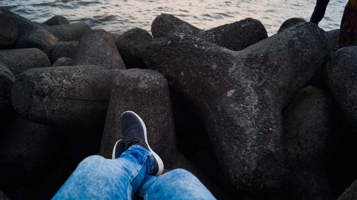 clothing person in blue denim jeans sitting infront of sea footwear