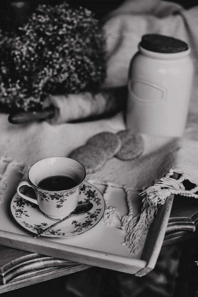 knot grayscale photography of teacup on a tray near cookies and jar grey