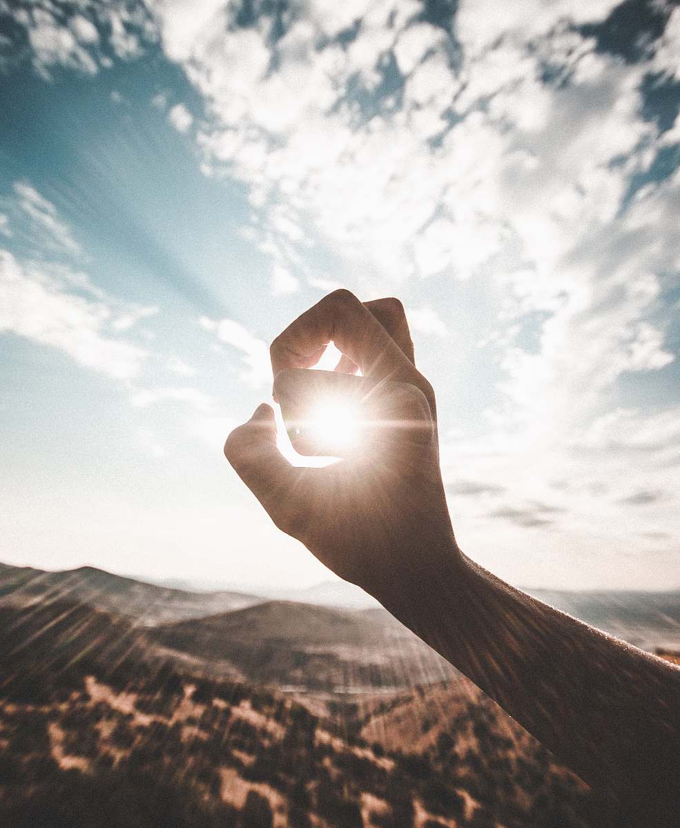 sunlight photography of sun glaring through the hole of finger weather