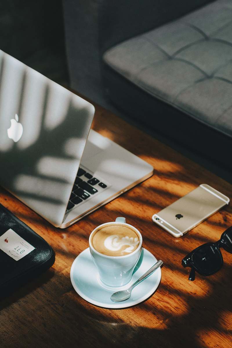 table cappuccino in white ceramic cup with saucer beside gold iPhone 6s and laptop coffee table