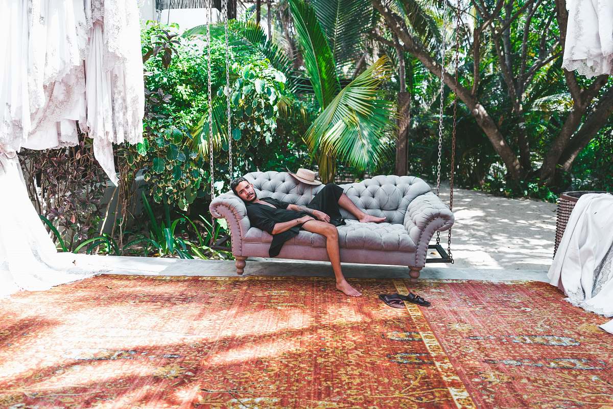 couch person in black robe lying on gray Chesterfield sofa chair