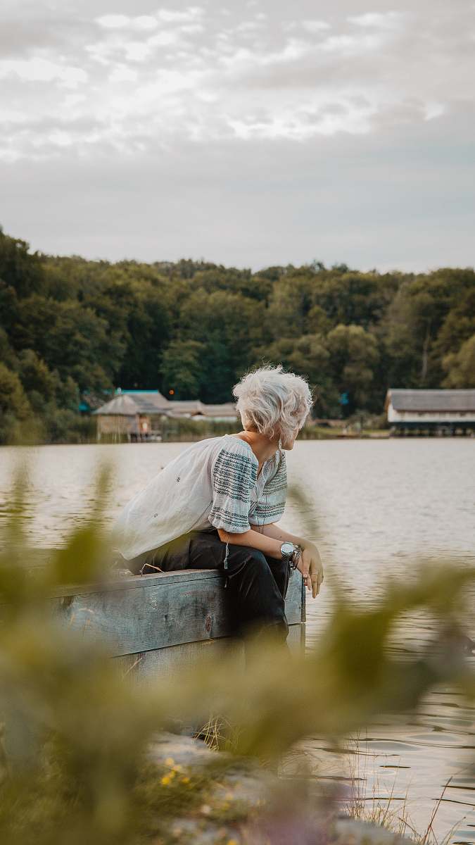 apparel man sitting on wooden dock during daytime clothing