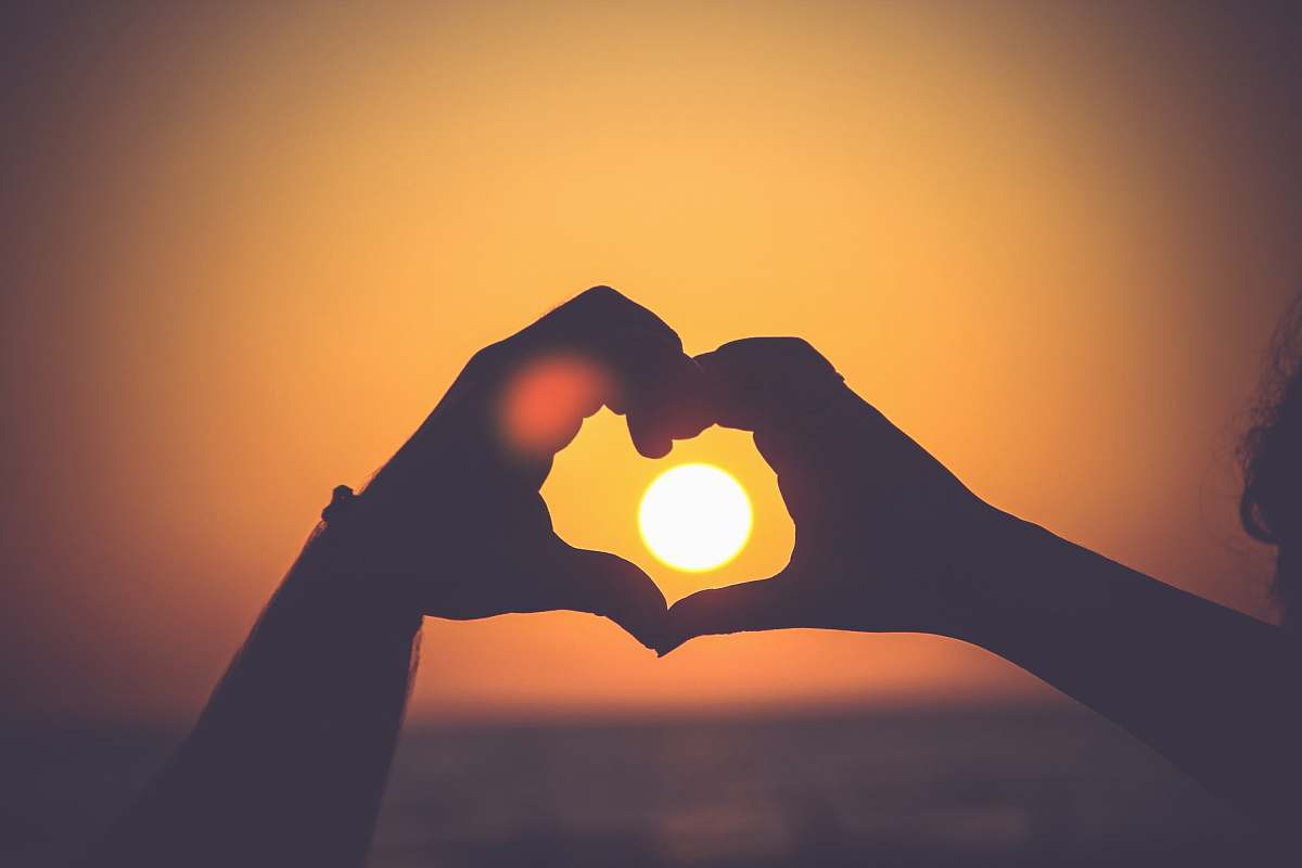 couple silhouette of person's hands forming heart hands