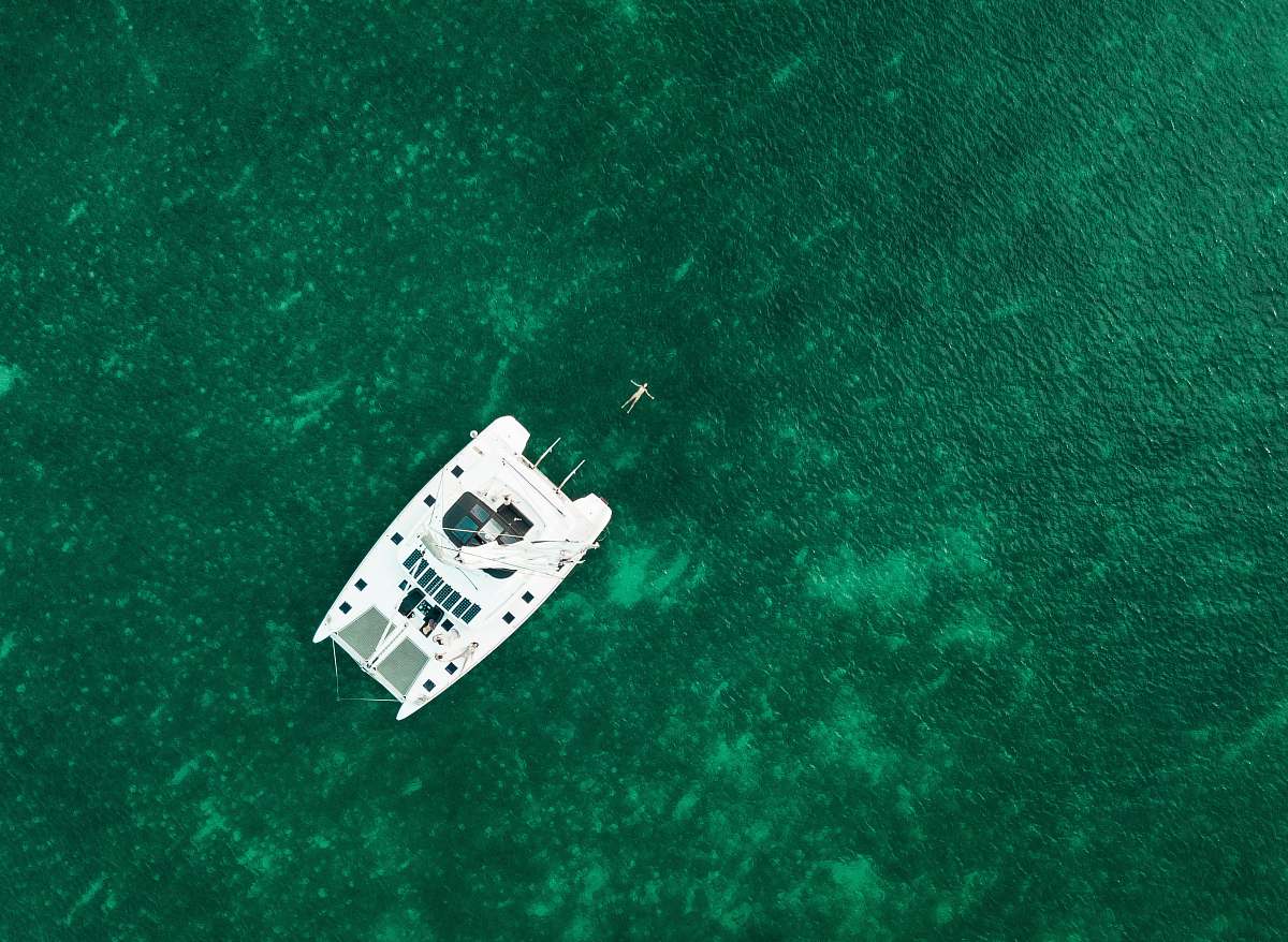 boat aerial view photography of white boat in the middle of body of water during daytime aerial view
