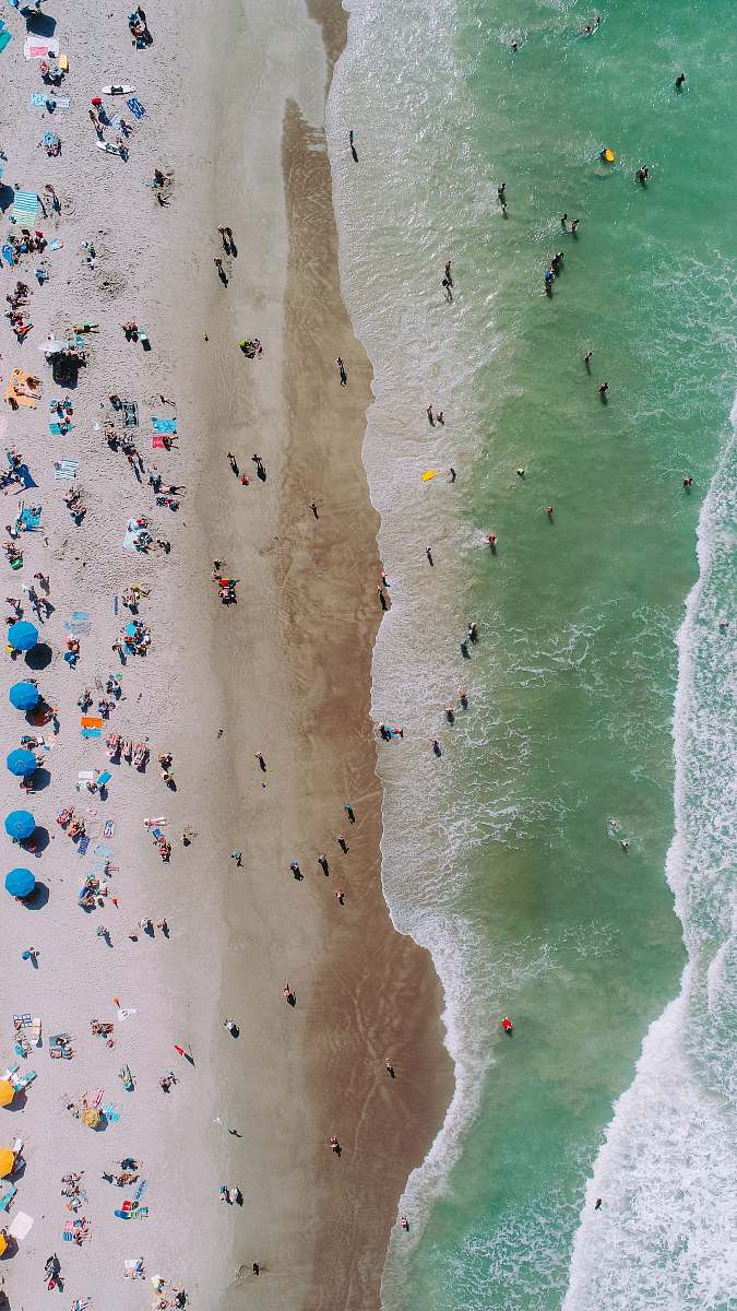 coast aerial photo of people on seashore during daytime photo beach