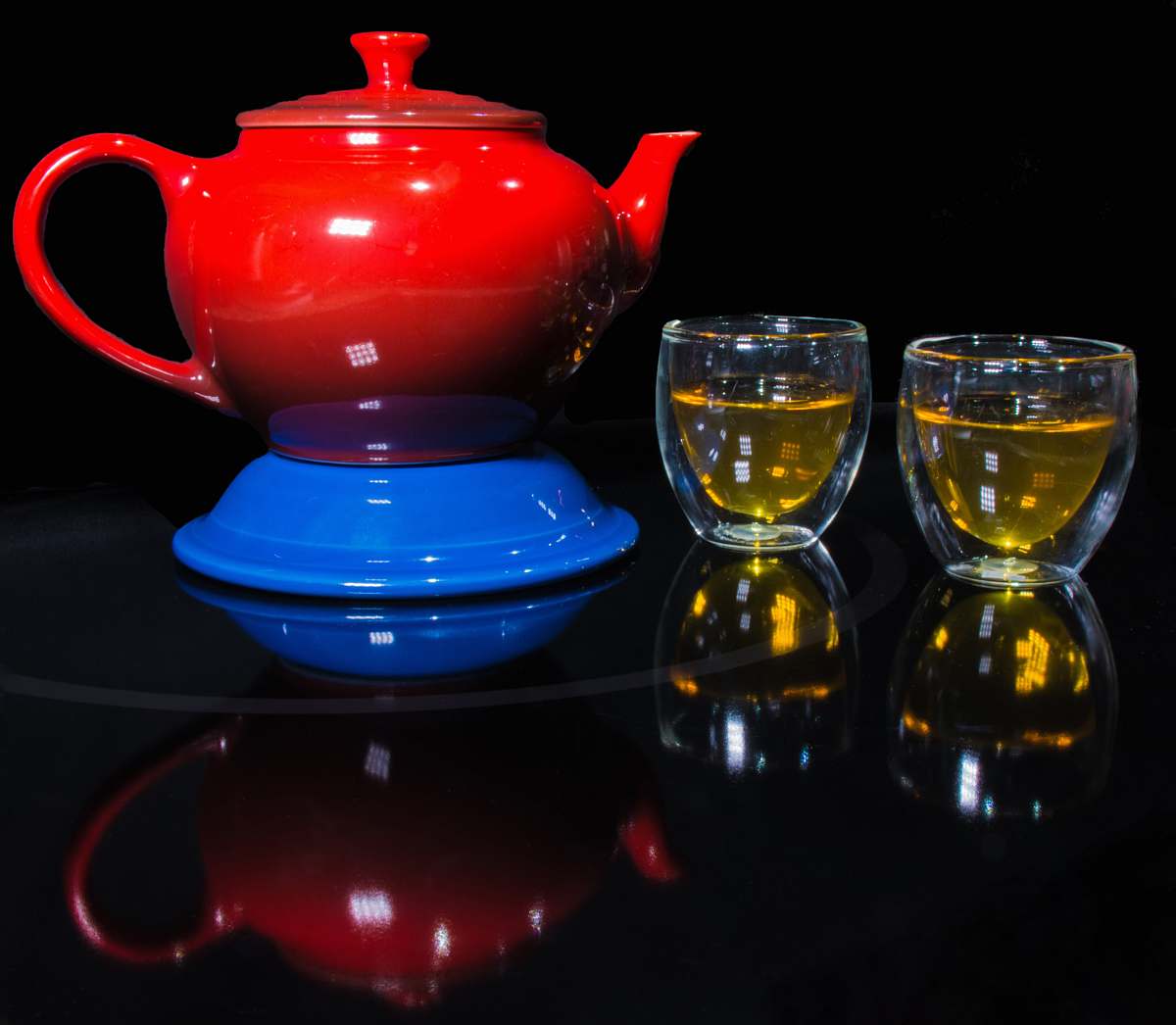 teapot red teapot on blue container beside two clear glass teacups pot